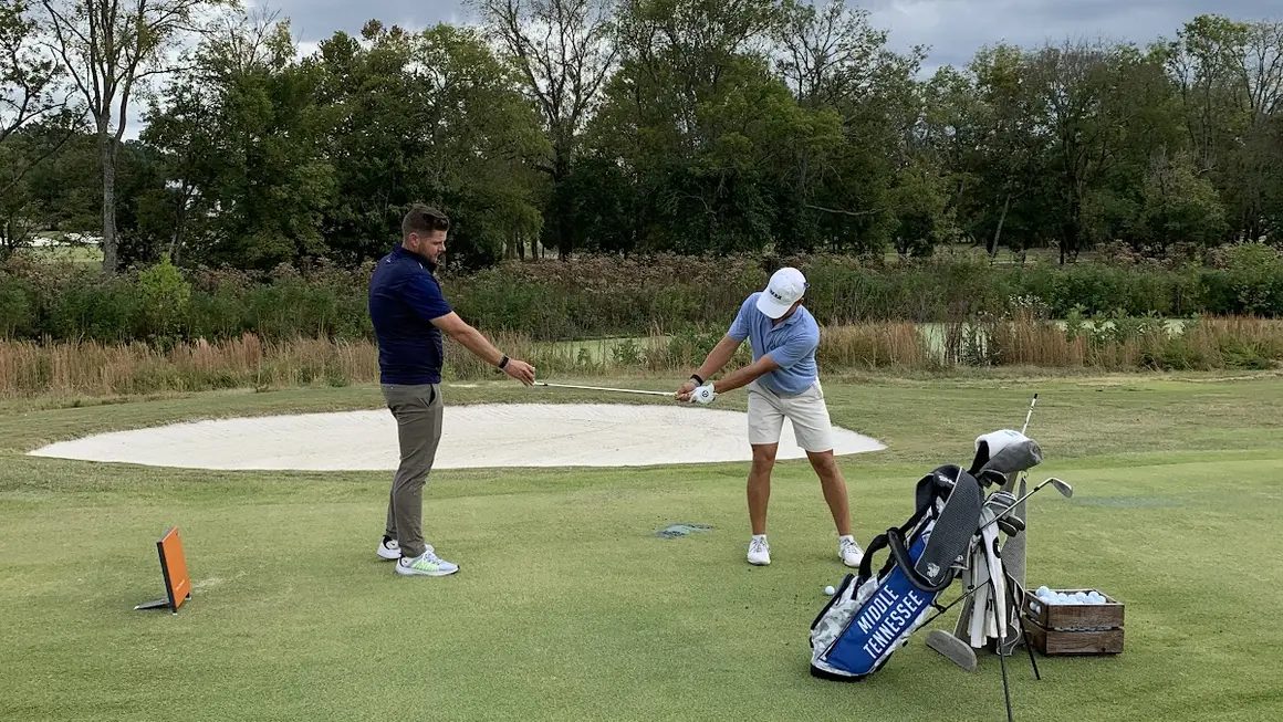 Jude Lenahan coaching a student through a shot from the tee
